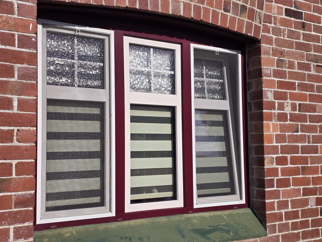 Heritage-style uPVC triple window with Georgian bar glazing and zebra blinds on a Federation-era brick home